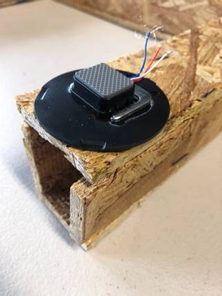 A black computer mouse on a piece of wood

Description automatically generated with low confidence