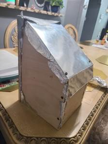 A wooden house with foil on it

Description automatically generated